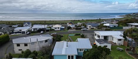 A coastal residential area with houses, a clear view of the sea, and a grassy lawn.