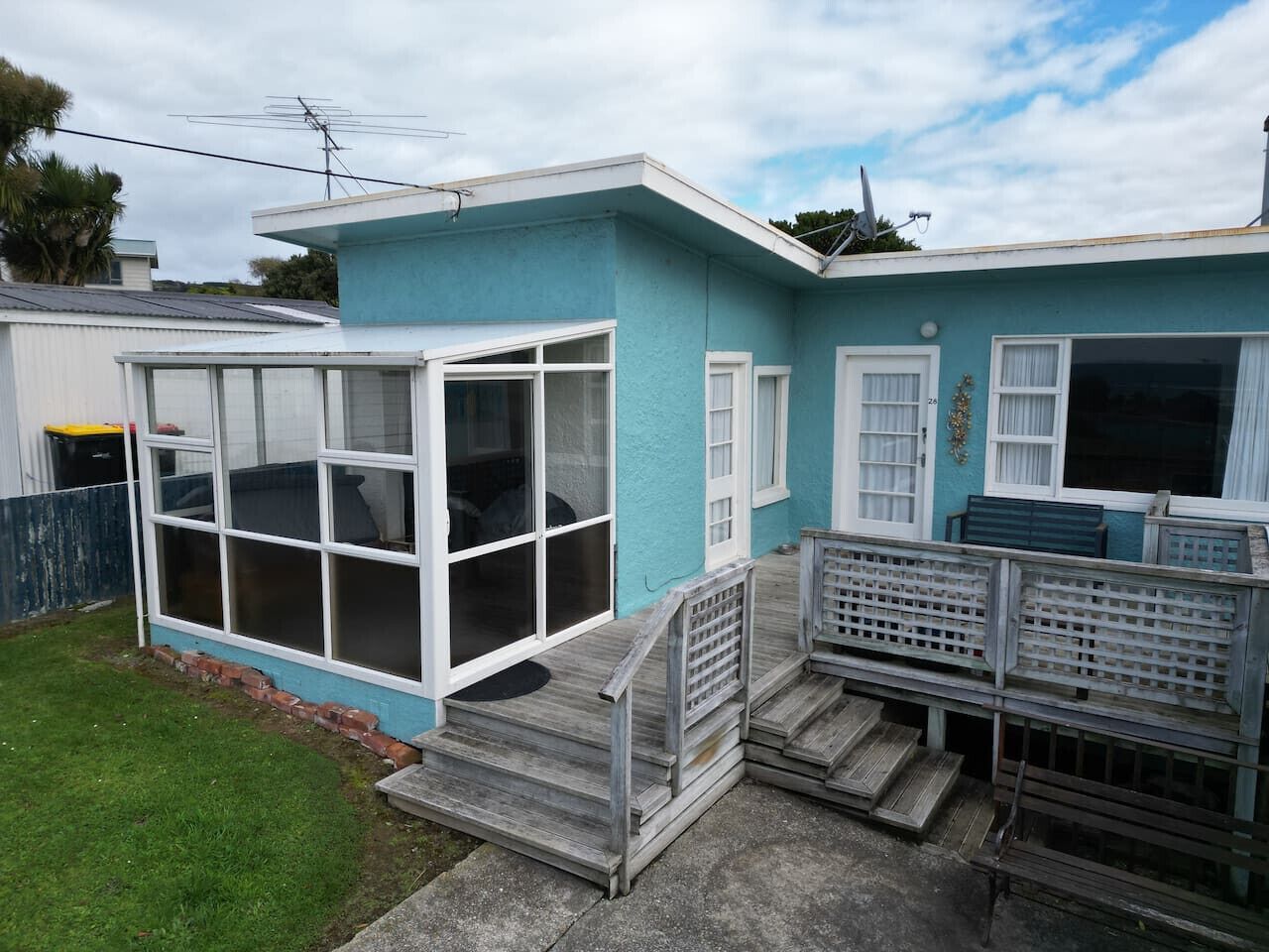 A two-story house with a blue exterior, a large glass door, and a wooden deck.