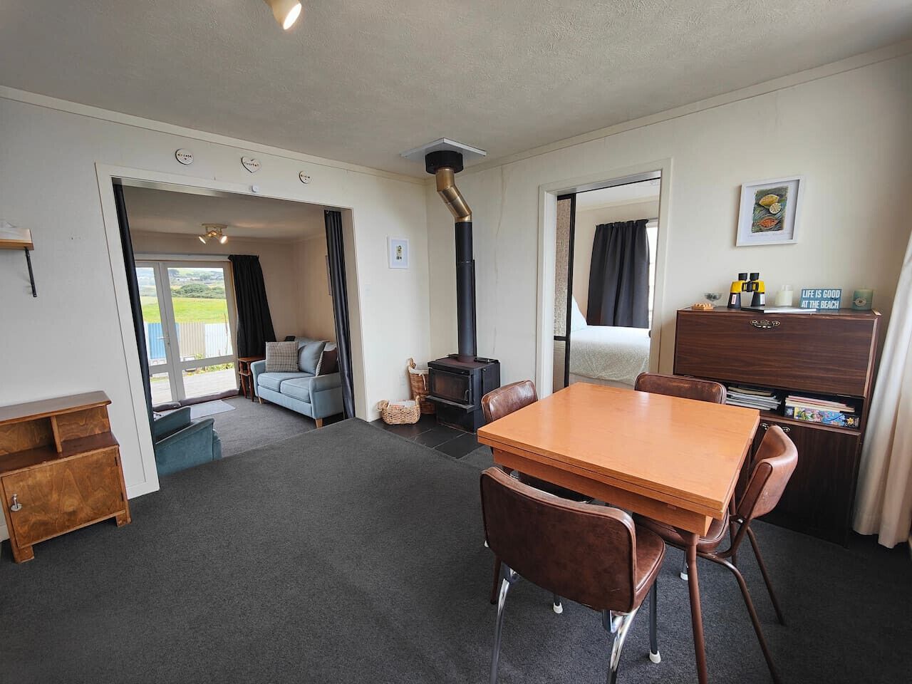 Een gezellige kamer met een houten tafel en stoelen, een bank, een open haard en uitzicht op de omgeving.