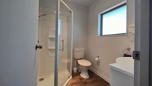 Un baño con cabina de ducha de vidrio, inodoro y lavamanos.