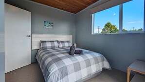Ein Schlafzimmer mit Bett, Nachttisch, Fenster und Deckenleuchte.