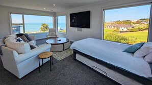 A modern bedroom with a bed, a sofa, a small round table, and a TV. - Riverton Helm`s Deep (Riverton / Aparima)