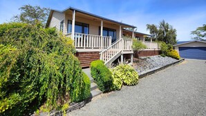 Une maison moderne de plain-pied dotée d’un porche couvert, d’un escalier d’entrée et d’un garage.
