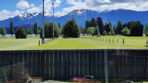 A view of a mountainous landscape with a clear sky, a grassy field, and a fence in the foreground. - Te Anau Retro Retreat (Te Anau)