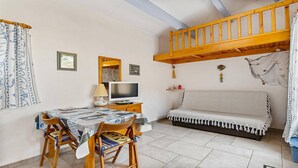 A cozy room with a bunk bed, a television, a table with chairs, and a sofa. - STUDIO MEZZANINE CLIMATISE POUR 4 PERSONNES (LE CAP D AGDE)