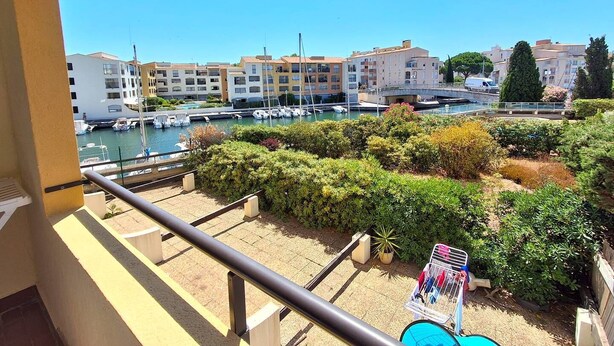 A balcony with a view of a marina, boats, and residential buildings. - STUDIO CABINE CLIMATISE AVEC CHAMBRE ALCÔVE (LE CAP D AGDE)