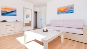 Ein modernes Wohnzimmer mit einem weißen Sofa, einem Couchtisch und Kunstwerken an den Wänden.