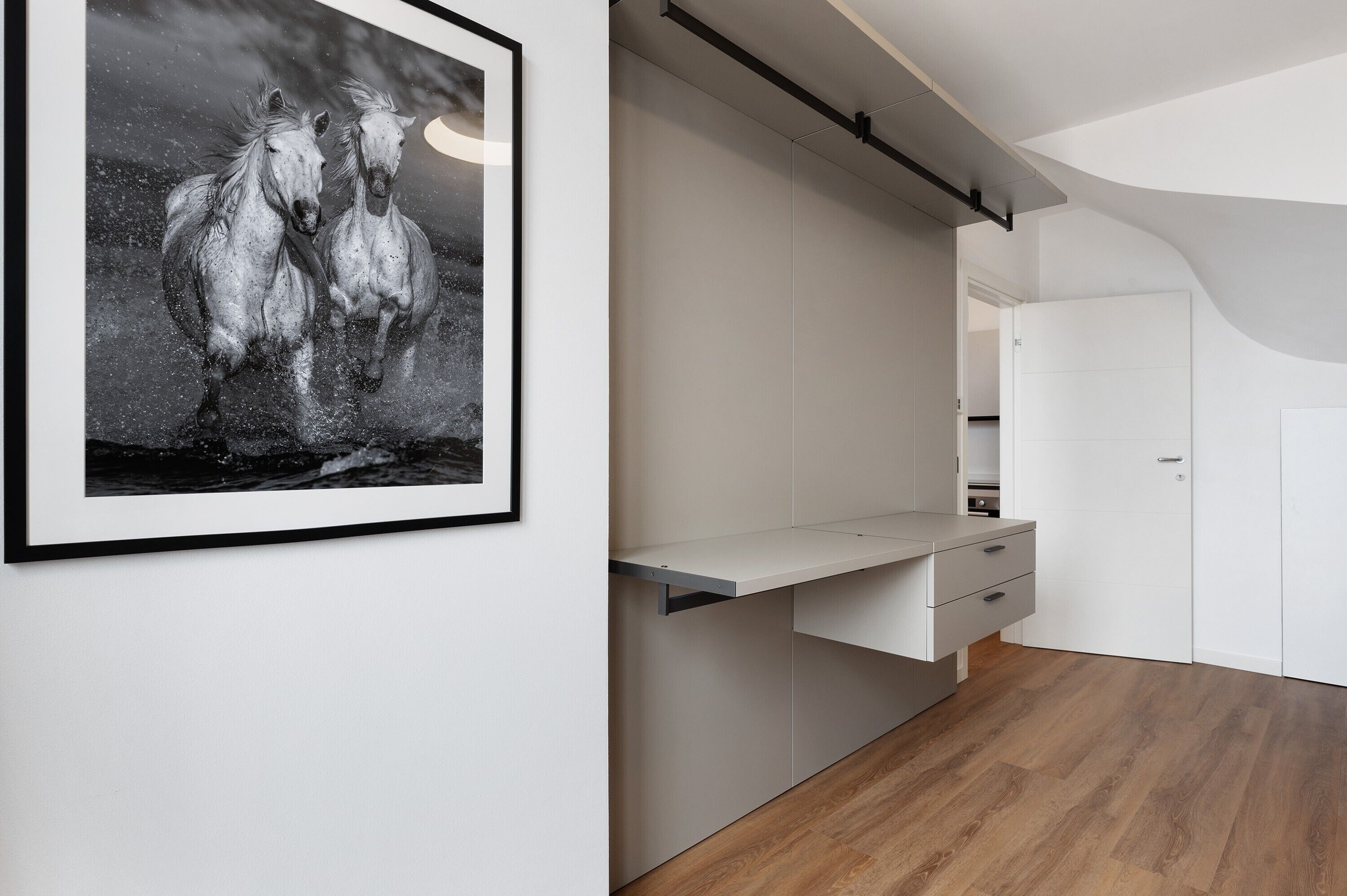 Eine moderne Küche mit weißen Schränken, einer Holzarbeitsplatte und einem gerahmten Schwarz-Weiß-Foto von einem Pferd an der Wand.