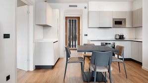 A modern kitchen with white cabinetry, a built-in microwave, and a dining area with a table and chairs. - Apartment 'Maso Renner 4' with Mountain View, Wi-Fi and Air Conditioning (Laives)