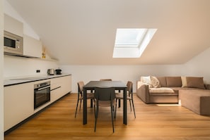 Eine moderne Küche mit Oberlicht, einem Esstisch mit Stühlen und einem Sofa in einem Wohnbereich.