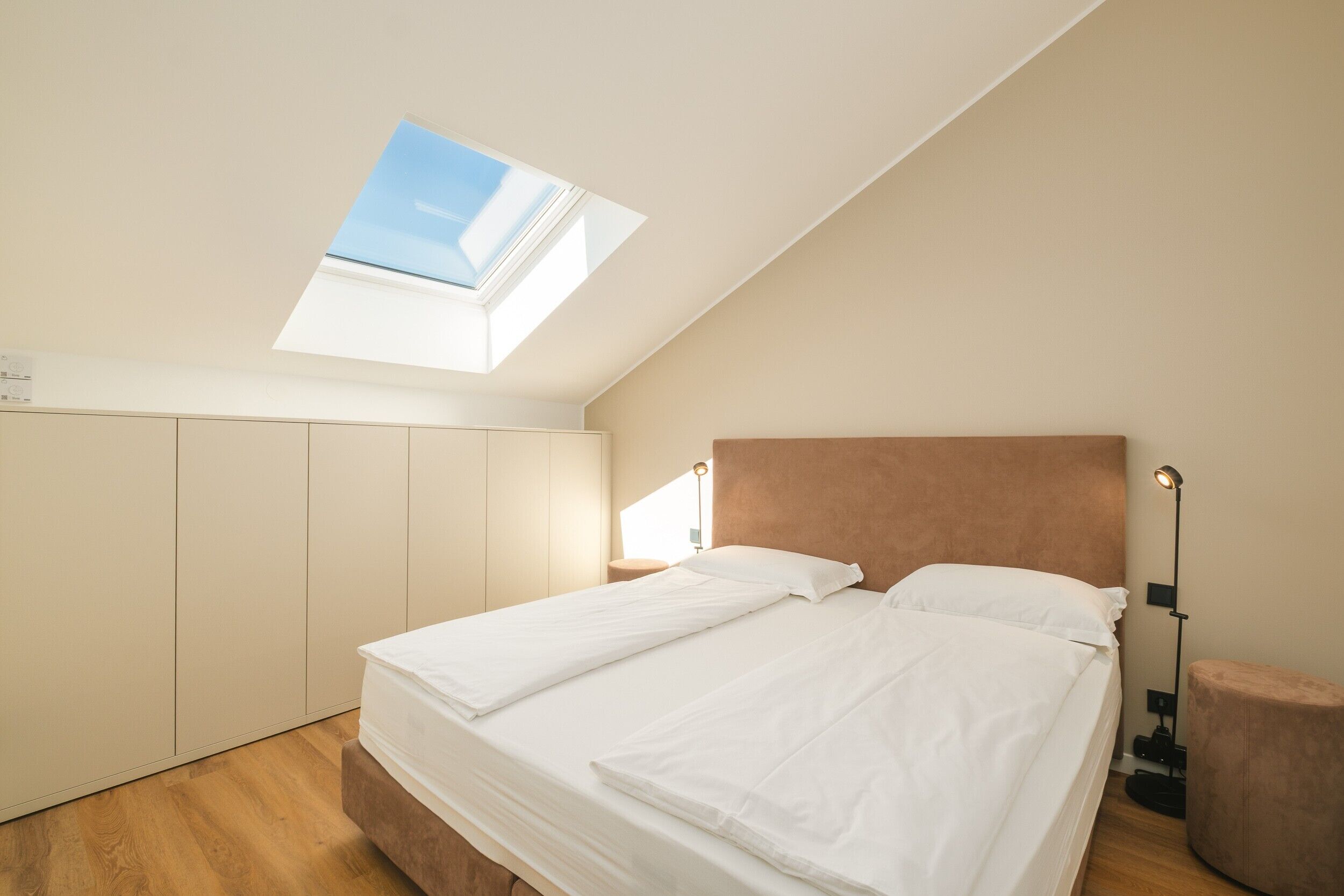 Een slaapkamer met dakraam, een bed, nachtkastje en lamp.