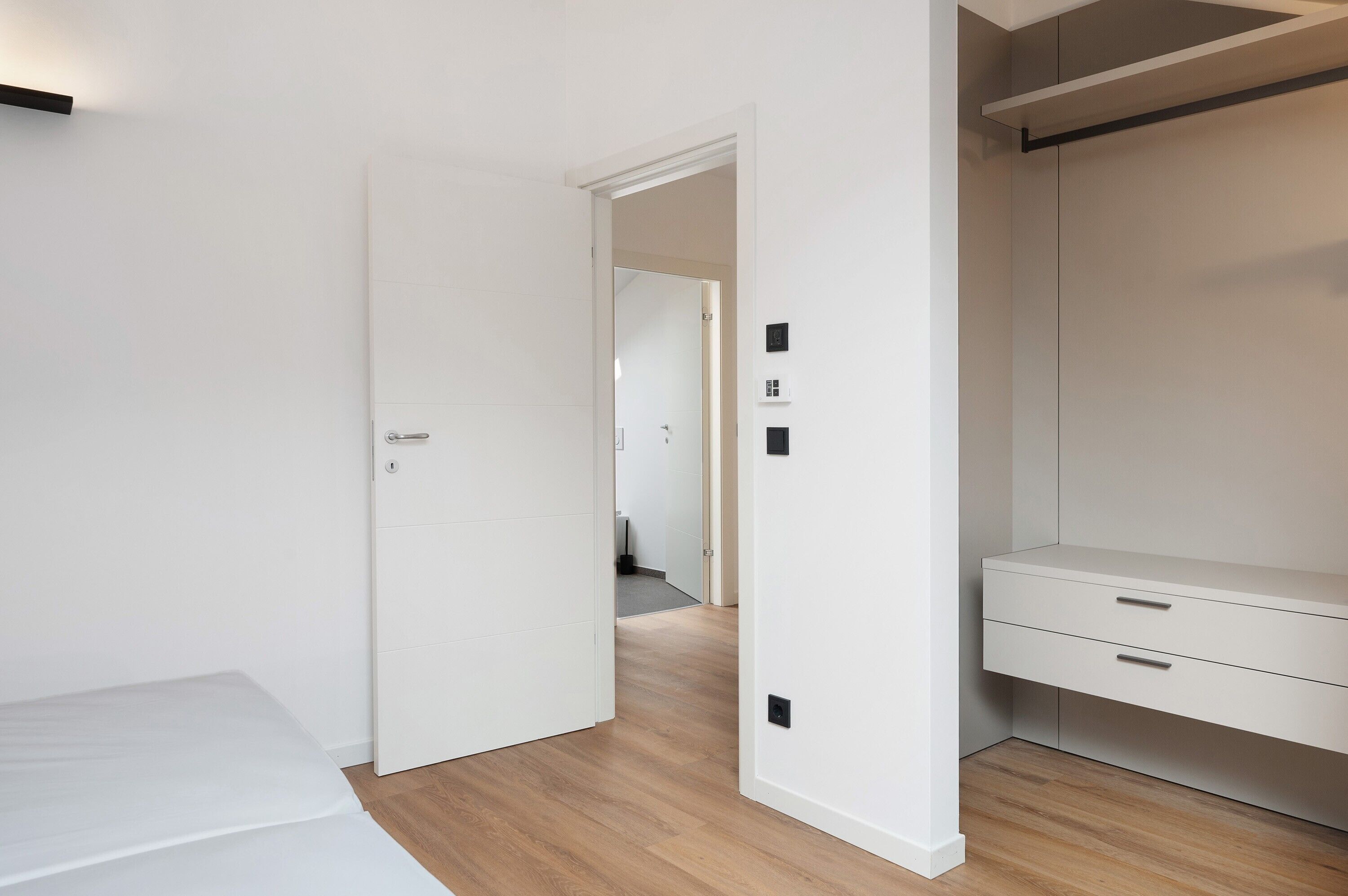 Une chambre à coucher comprenant un lit, une armoire et une porte donnant sur une autre pièce.