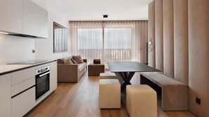 A modern kitchen with a dining area, a sofa, and a large window with curtains. - Apartment 'Maso Renner 6' with Mountain View, Wi-Fi and Air Conditioning (Laives)