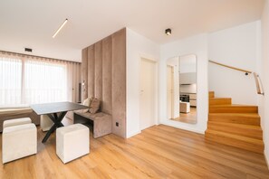 A modern interior with a dining area, a staircase, and a kitchen visible through an open door.