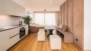 A modern kitchen with a built-in oven, a dining area with a table and benches, and a large window with sheer curtains. - Apartment 'Maso Renner 6' with Mountain View, Wi-Fi and Air Conditioning (Laives)