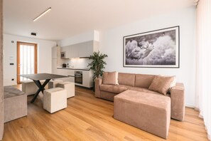 A modern living room with a sofa, ottoman, and a dining table.