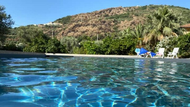 A clear swimming pool with visible ripples, surrounded by greenery and a hill in the background. - Apartment 'Ulivo' with Mountain View, Wi-Fi and Air Conditioning (Terrazze)
