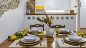 A dining table set with plates, glasses, and cutlery, a vase with dried plants, and a kitchen in the background. - Apartment 'Ulivo' with Mountain View, Wi-Fi and Air Conditioning (Terrazze)