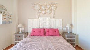 Une chambre à coucher comprenant un lit, deux tables de chevet, un attrape-rêves fixé au mur et une commode.