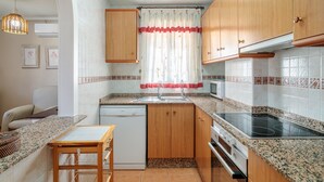 Une cuisine de taille réduite, dotée de meubles en bois, d’un lave-vaisselle, d’un four à micro-ondes et d’une cuisinière.