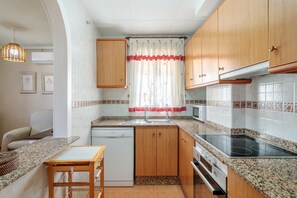 A compact kitchen with wooden cabinets, a dishwasher, a microwave, and a stove.