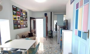 A compact living space with a kitchenette, a dining area, and a wall adorned with photographs.