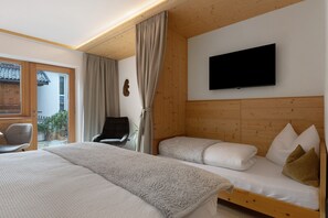 A bedroom with a bed, a chair, a TV, and a wooden ceiling. - Apartment ‘Charly’ with Mountain View, Private Garden, and Wi-Fi (San Martino)