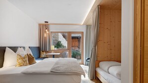 A bedroom with a large bed, a smaller bed, a desk, and a view of the outside. - Apartment ‘Charly’ with Mountain View, Private Garden, and Wi-Fi (San Martino)