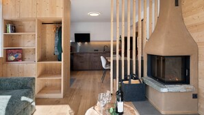 A modern interior with a wooden bookshelf, a dining area, and a fireplace. - Apartment ‘Charly’ with Mountain View, Private Garden, and Wi-Fi (San Martino)