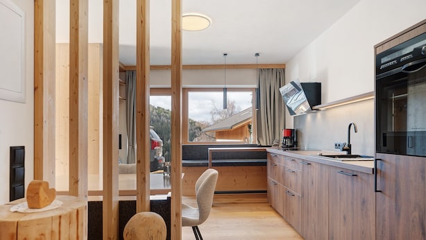 A modern kitchen with wooden cabinets, a built-in oven, and a large window. - Apartment ‘Charly’ with Mountain View, Private Garden, and Wi-Fi (San Martino)