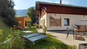 A chalet with a patio area, outdoor seating, and a mountain view. - Apartment ‘Charly’ with Mountain View, Private Garden, and Wi-Fi (San Martino)