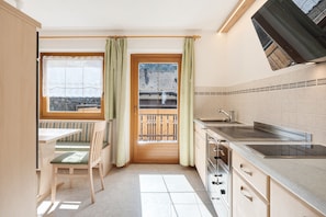 Une cuisine avec une fenêtre, un coin repas avec une table et des chaises, et une vue sur un bâtiment traditionnel.