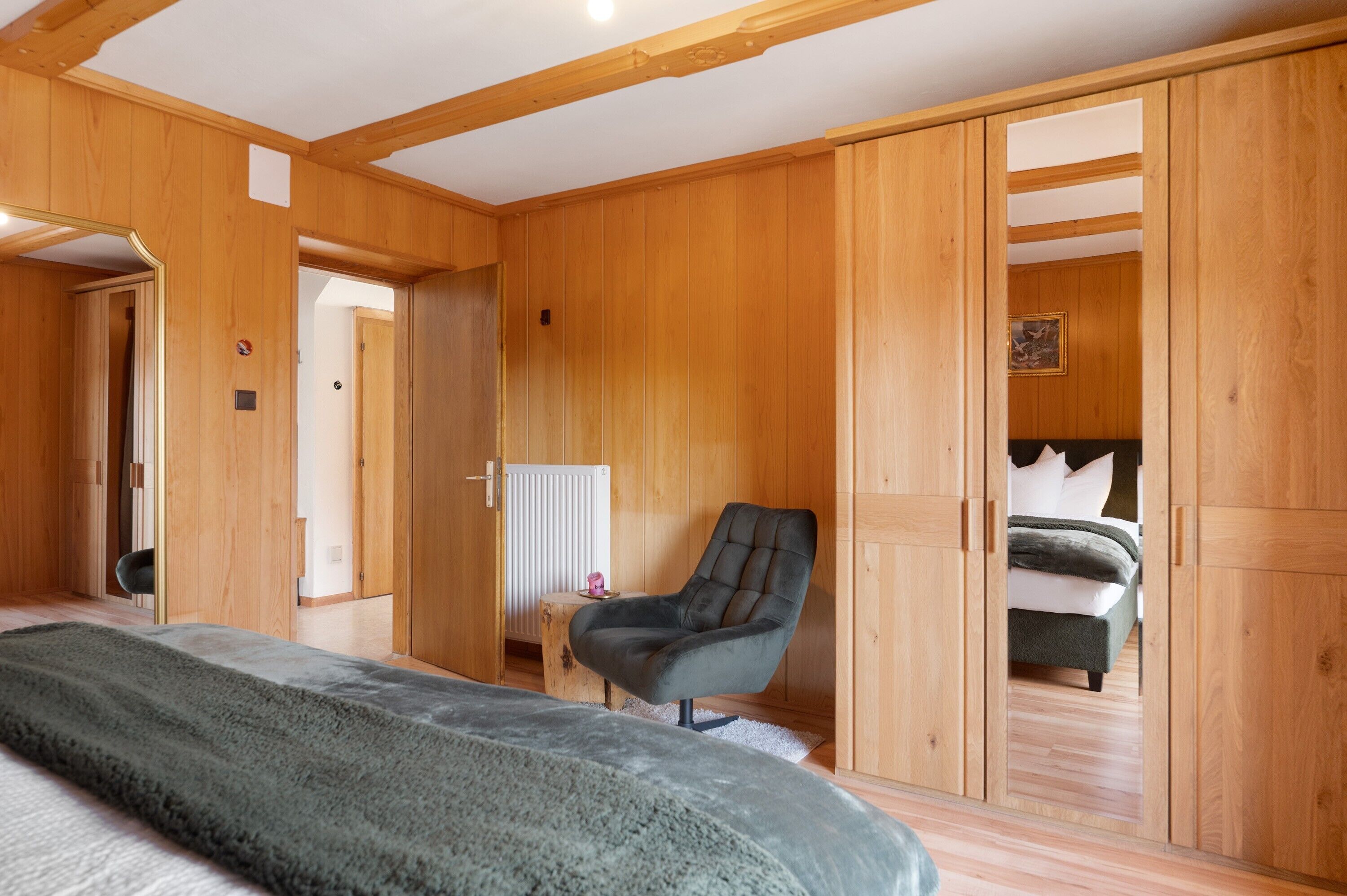 A room with wooden walls, a bed, a chair, and a radiator.