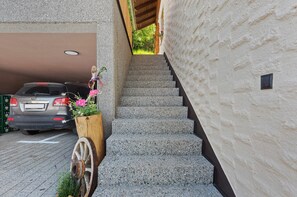 Una escalera que conduce a un edificio con un coche estacionado en un garaje.