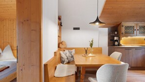 Ein Holztisch mit Bänken, eine Pendelleuchte und eine Vase mit Blumen.