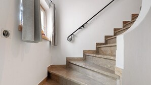 Eine Treppe mit Marmorstufen und einer Metallhandläufe, die zu einem Zwischenpodest mit Lichtschalter und Steckdose führt.