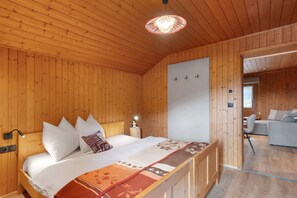 Une pièce aux murs lambrissés, avec un lit, une lampe de chevet et un luminaire suspendu.