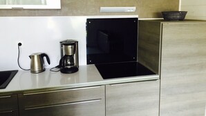Une petite cuisine équipée d’une cuisinière en acier inoxydable, d’une machine à café et d’une bouilloire.