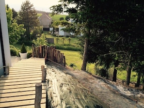 Um deck de madeira leva a uma área gramada, com um edifício branco ao fundo.