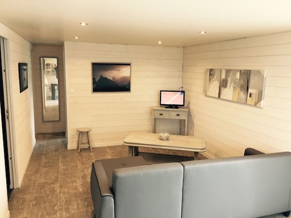 Quarto moderno com televisão de tela plana, uma pequena mesa, um banco e um quadro na parede.