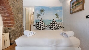 Una cama con dos almohadas, vista al mar y un cuadro en la pared.
