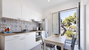 Une cuisine moderne avec des meubles blancs, un pare-feu en carreaux et un coin repas comprenant une table et des chaises.