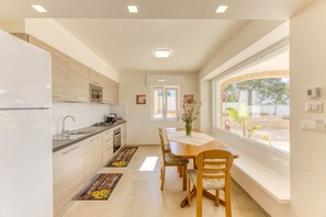 A modern kitchen with a dining area, a large window, and a view of the outdoors.