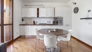 Una cocina moderna con armarios blancos, una mesa de comedor redonda y sillas blancas.