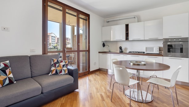 Un apartamento moderno con sofá, mesa de comedor y zona de cocina.
