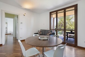A modern dining area with a round table, white chairs, and a view through large sliding doors to an outdoor patio. - Apartment 'La Casa Di Cami' with Balcony and Wi-Fi (Agrate Brianza)