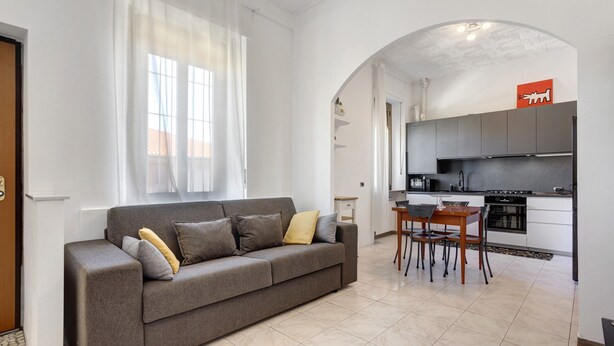 Un salon moderne avec un canapé, une table à manger et une cuisine en arrière-plan.