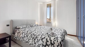 Une chambre moderne avec un lit, une table de chevet, une armoire et une fenêtre avec des rideaux.