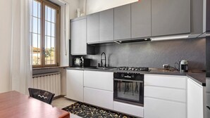 Une cuisine moderne équipée d’une cuisinière, d’un four et d’un évier, d’une table à manger et d’une fenêtre avec des rideaux.