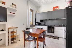 Une cuisine compacte dotée d’appareils électroménagers modernes, une table à manger avec des chaises et un petit meuble de rangement.